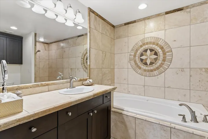 Bathroom with tile walls, a garden tub, vanity, recessed lighting, and tiled shower