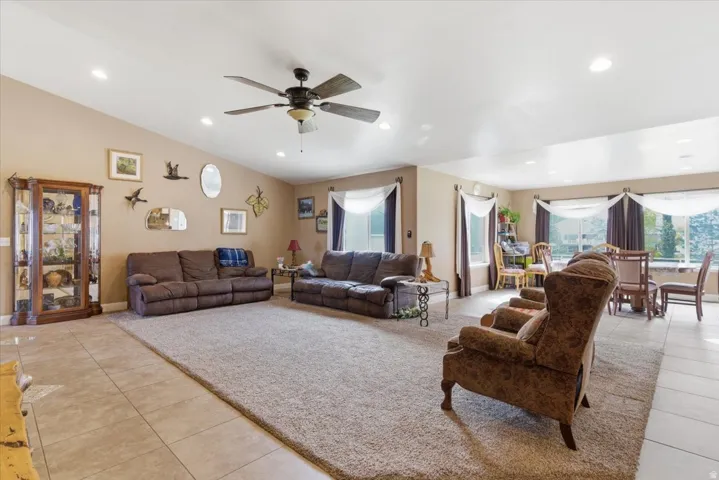 Living room with light tile patterned floors, ceiling fan, recessed lighting, plenty of natural light, and vaulted ceiling
