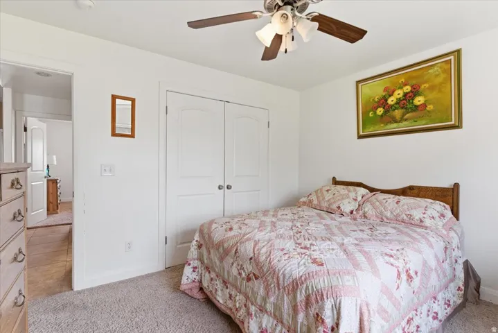 Bedroom featuring light colored carpet, a closet, and ceiling fan
