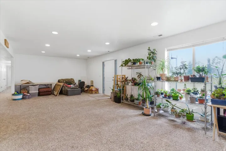 Living area with light carpet and recessed lighting