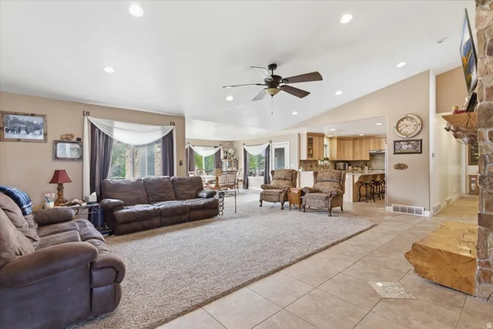 Living area featuring ceiling fan, healthy amount of natural light, vaulted ceiling, recessed lighting, and light tile patterned floors