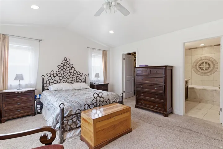 Bedroom featuring light colored carpet, a walk in closet, lofted ceiling, ceiling fan, and recessed lighting