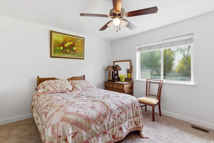 Bedroom with light colored carpet and a ceiling fan