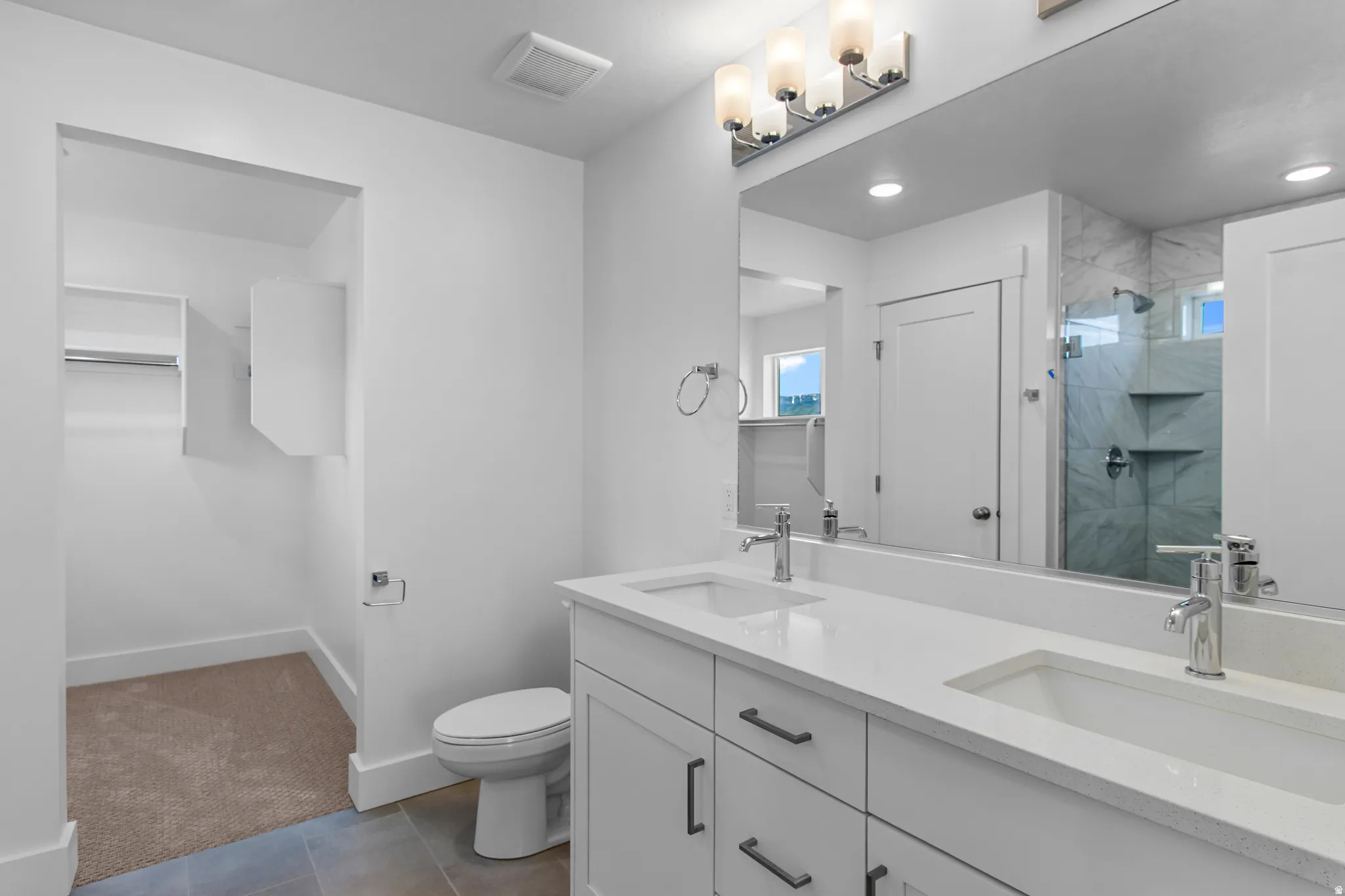 Bathroom with double vanity, a stall shower, dark tile patterned floors, recessed lighting, and a walk in closet