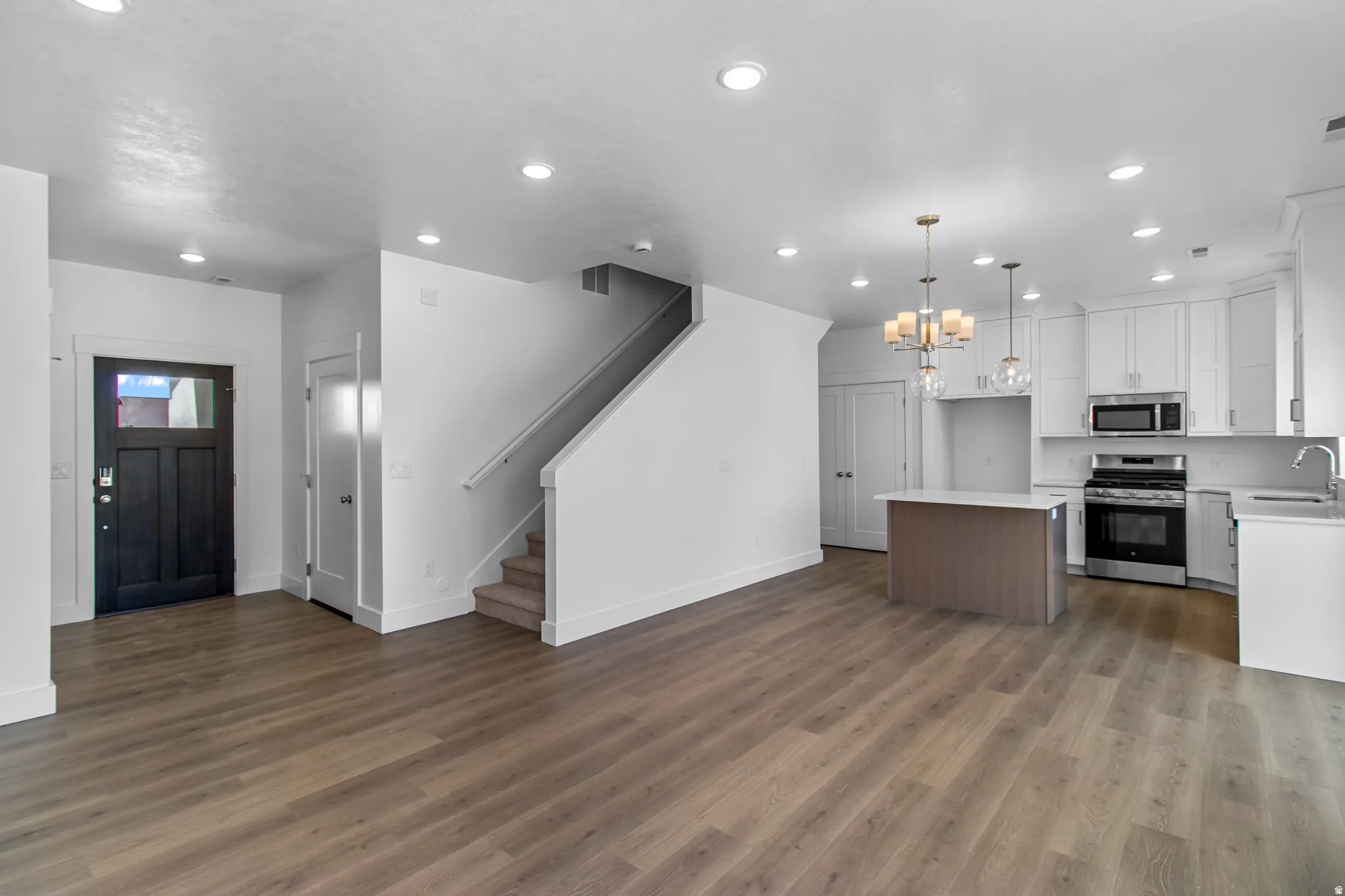 Kitchen with open floor plan, stainless steel appliances, hanging lights, a center island, and white cabinetry