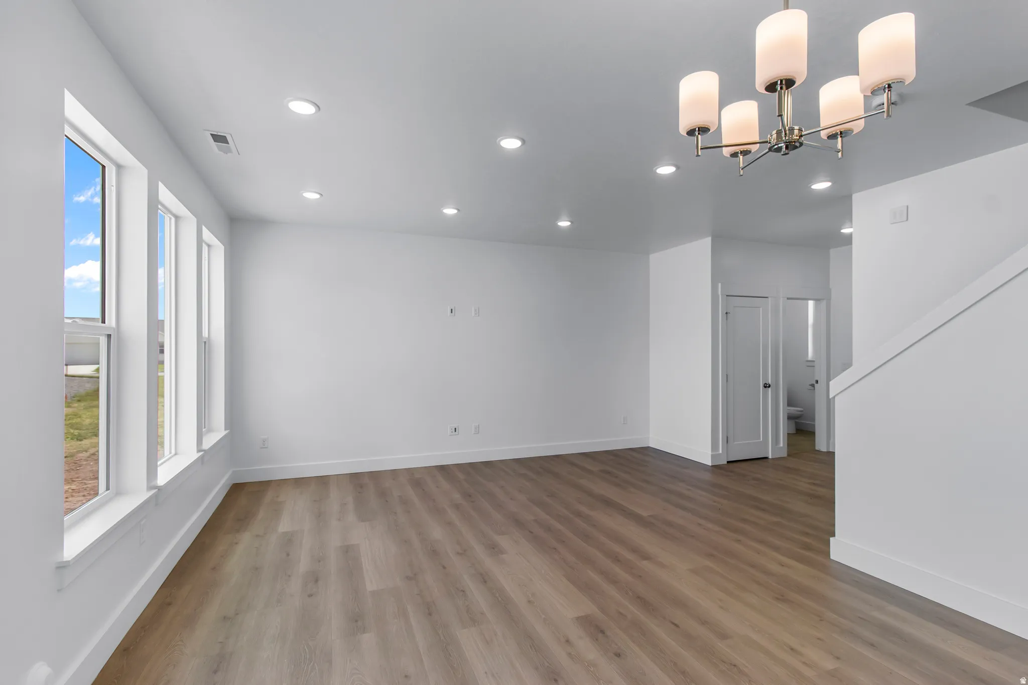 Spare room with light wood-style floors and hanging lights