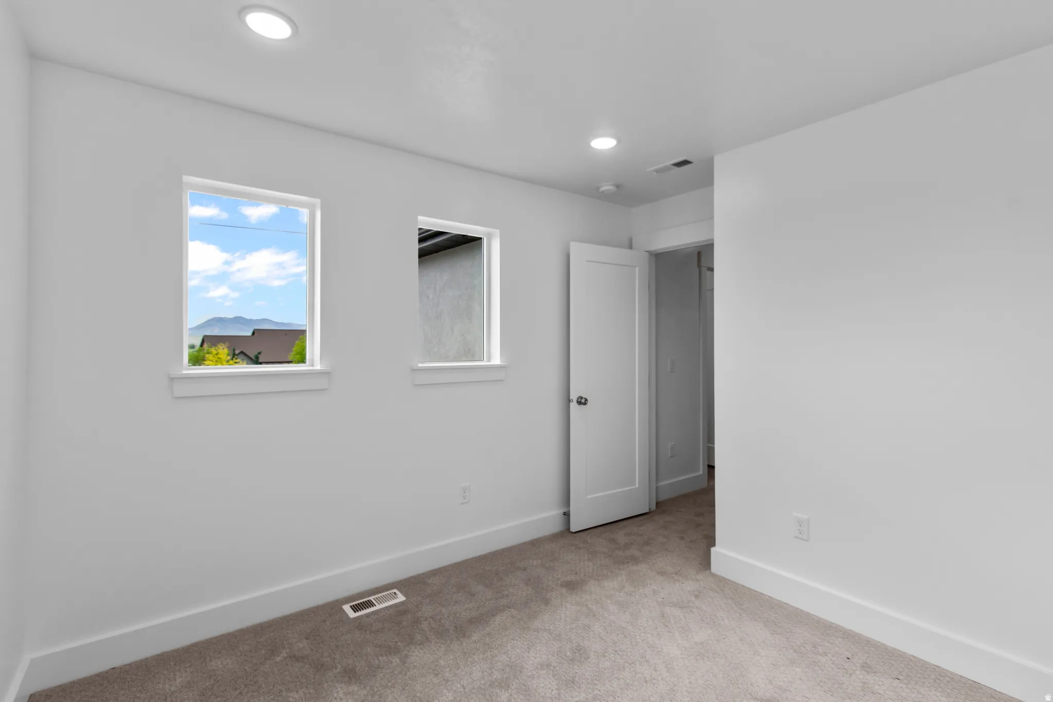 Carpeted empty room with baseboards and recessed lighting