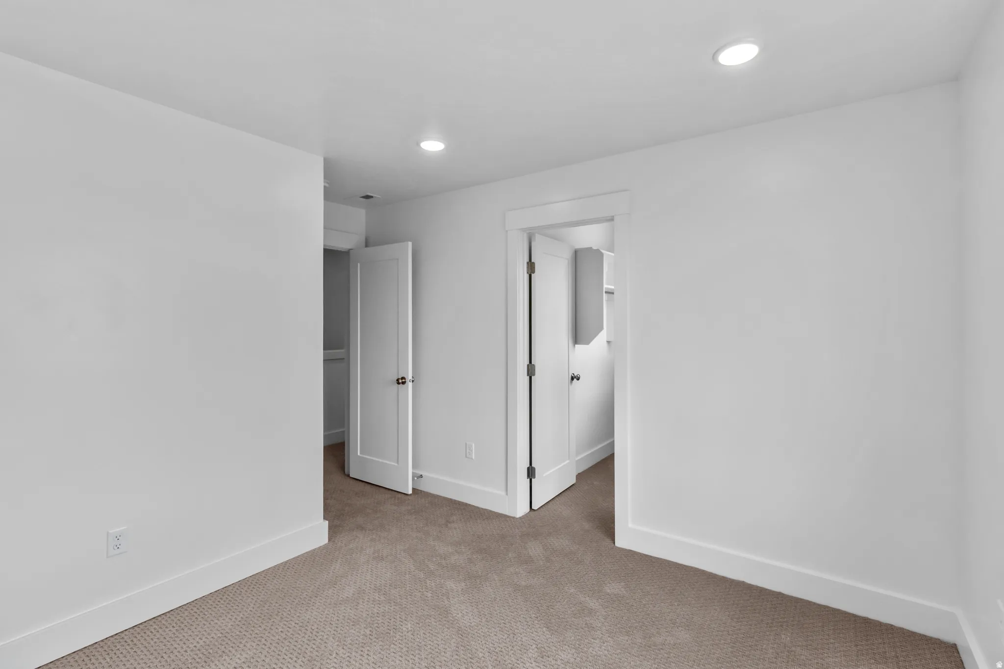 Unfurnished bedroom featuring a spacious closet, recessed lighting, and light colored carpet
