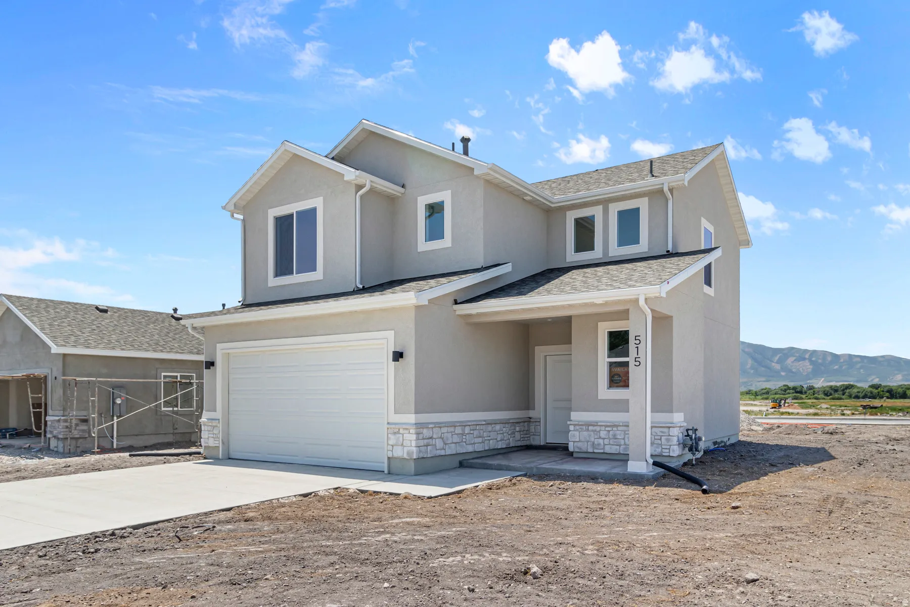 View of front of home with a garage, stucco siding, driveway, stone siding, and a shingled roof