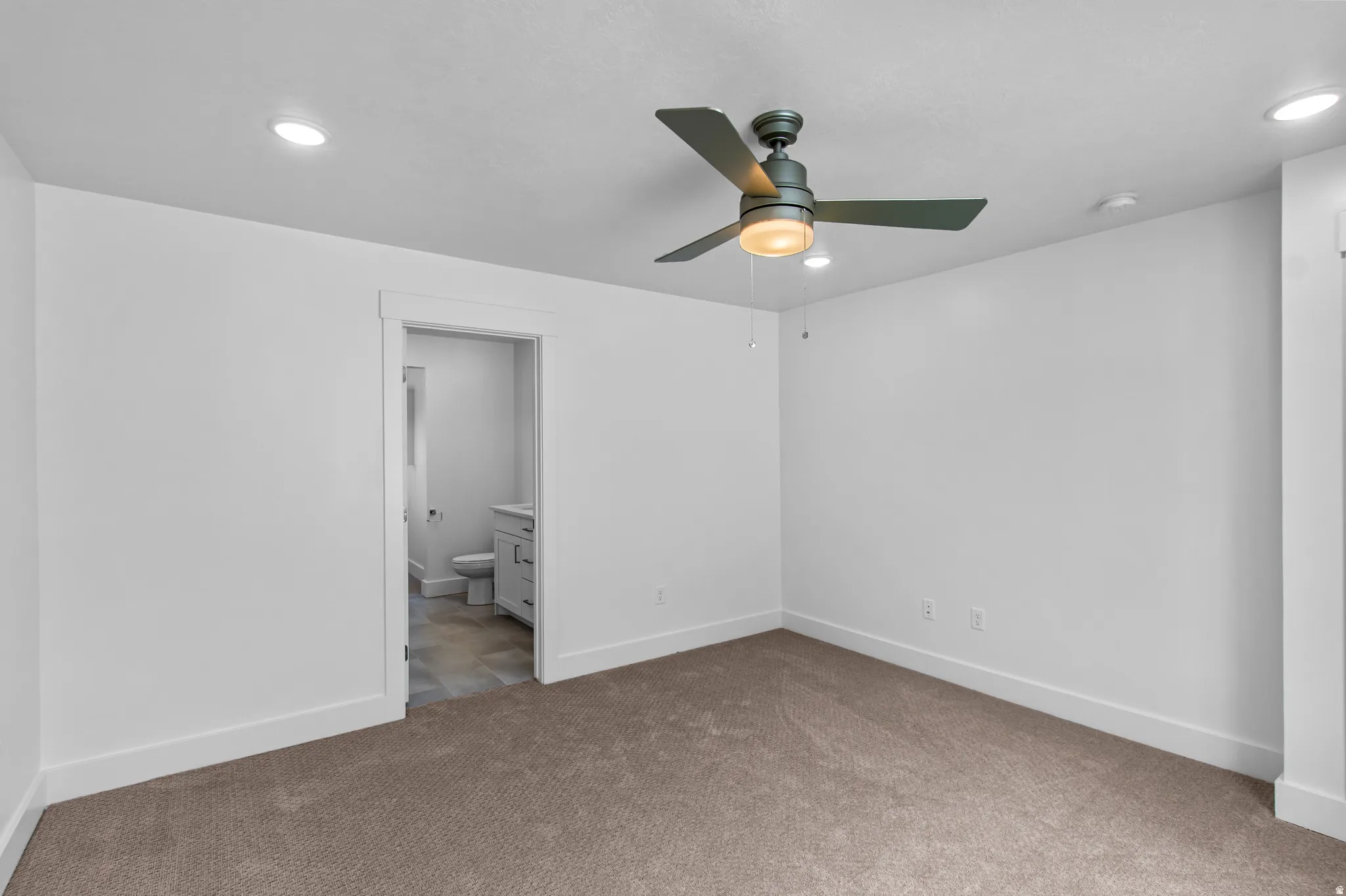Unfurnished bedroom featuring carpet, ensuite bathroom, ceiling fan, and recessed lighting