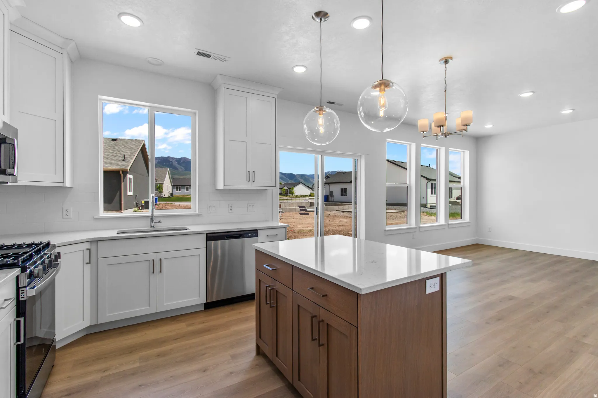 Two tone kitchen with two tone cabinetry, stainless steel appliances, light wood-style flooring, and tasteful backsplash