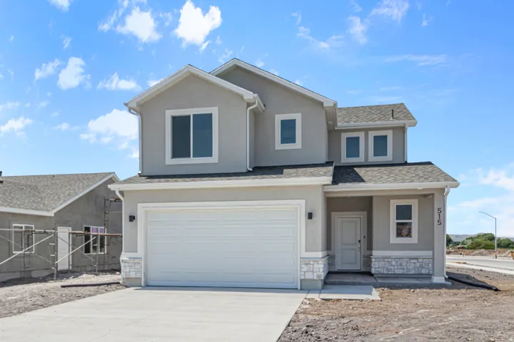 View of front of property featuring stucco siding, a garage, and covered porch
