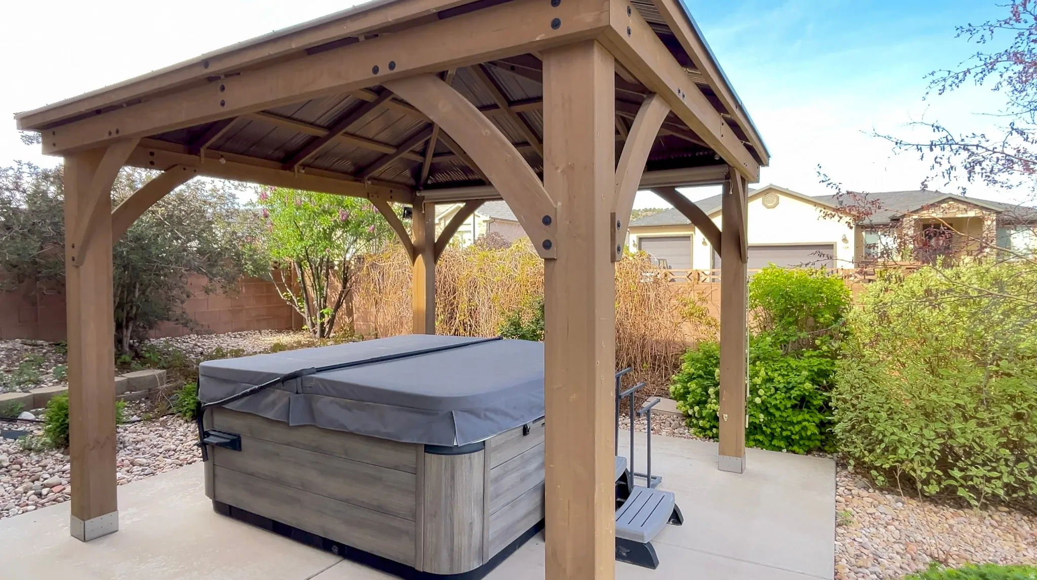 Fenced backyard with a gazebo, a patio, and a hot tub
