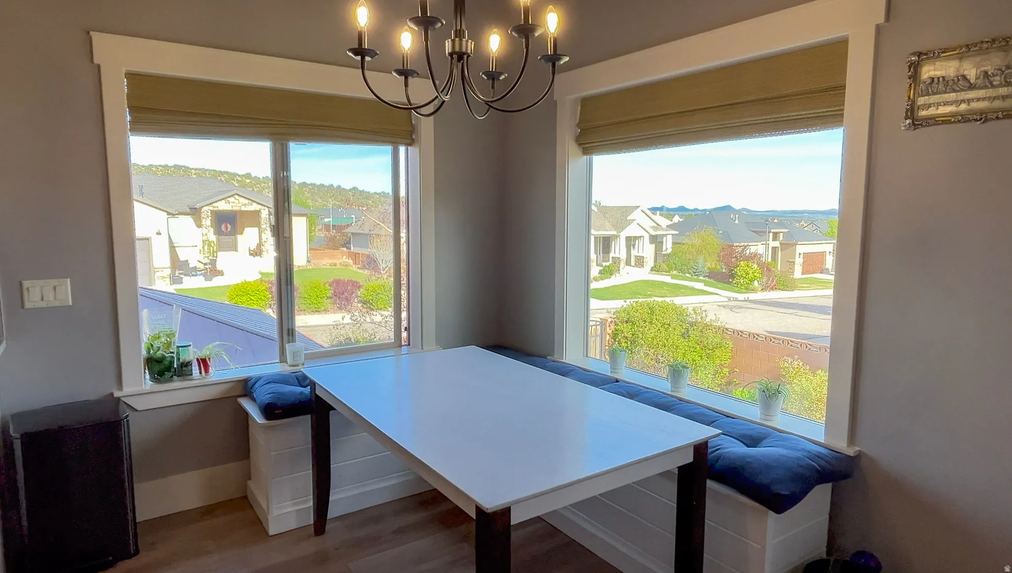 Dining space featuring suspended lighting, wood finished floors, and a residential view