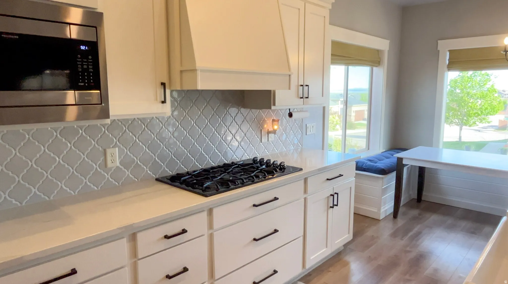 Kitchen featuring stainless steel microwave, white cabinetry, light wood-type flooring, and black gas stovetop