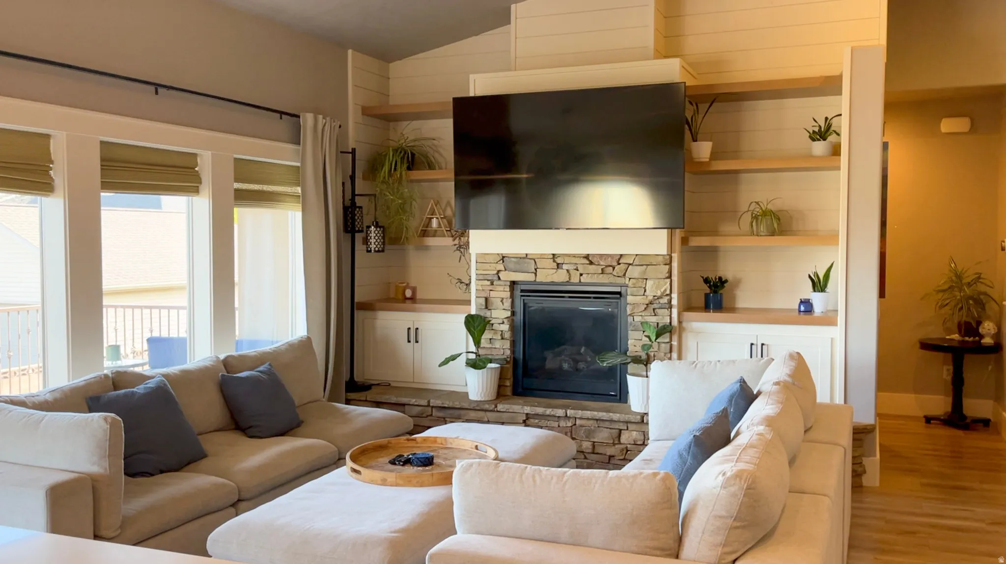 Living room with a fireplace, light wood finished floors, and vaulted ceiling