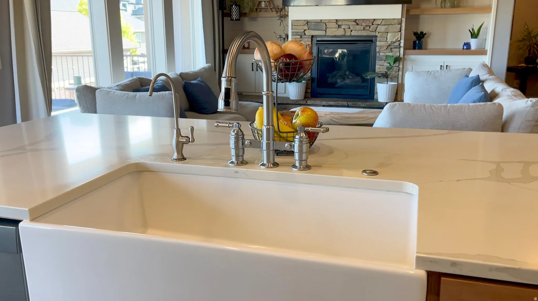 Kitchen view of a fireplace, light stone countertops, and dishwasher