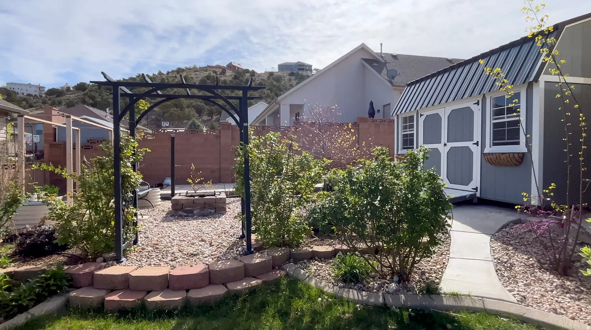 Rear view of house with a storage unit, stucco siding, a metal roof, and a fire pit