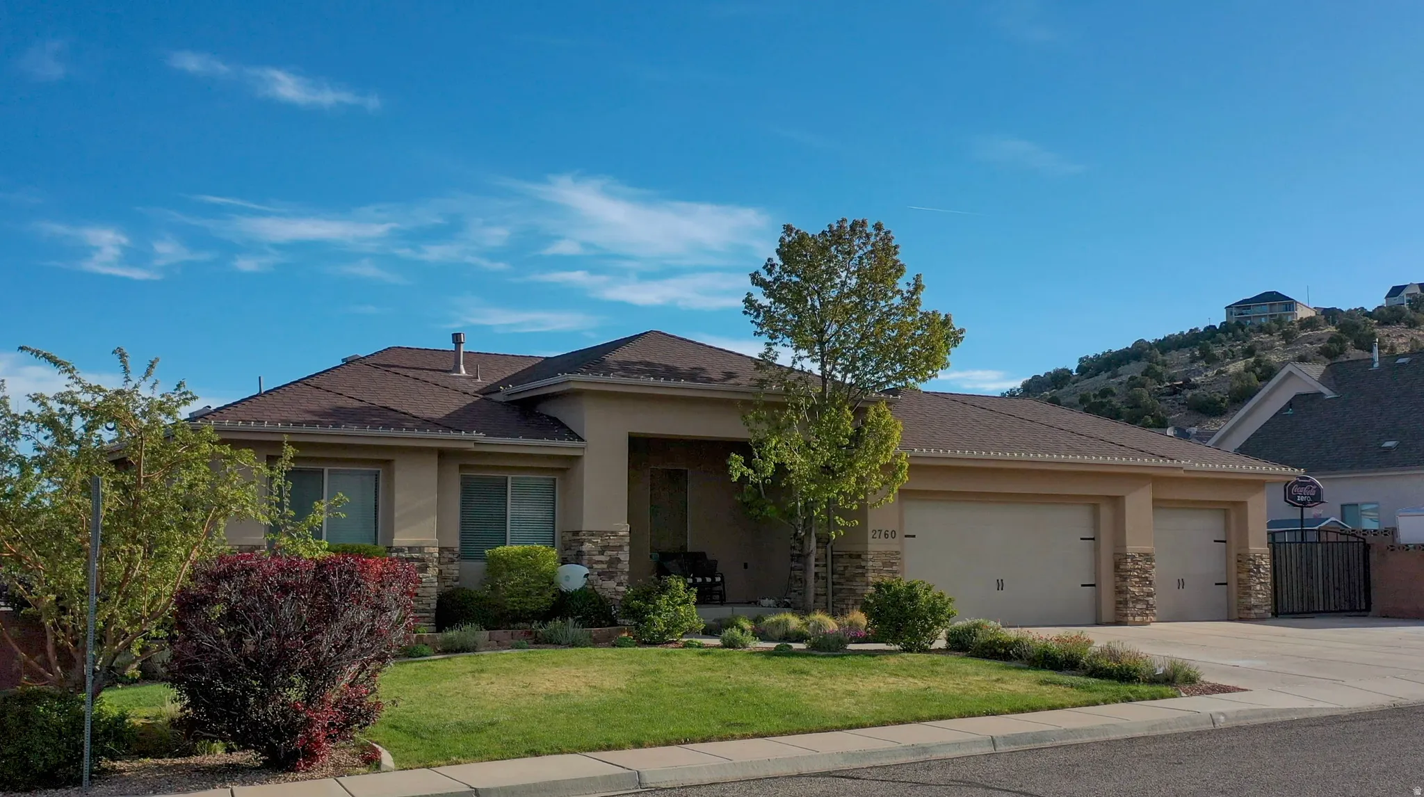 View of front of home featuring stone siding, stucco siding, an attached garage, and a front yard