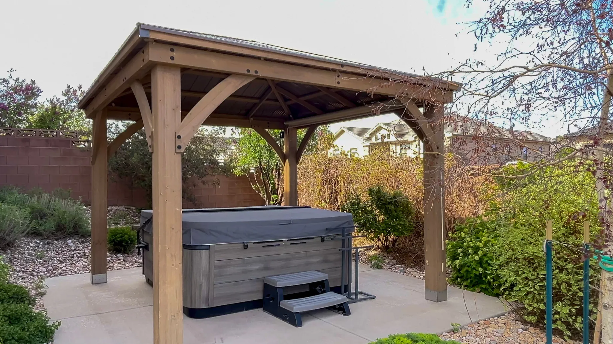 Fenced backyard with a patio area, a gazebo, and a hot tub
