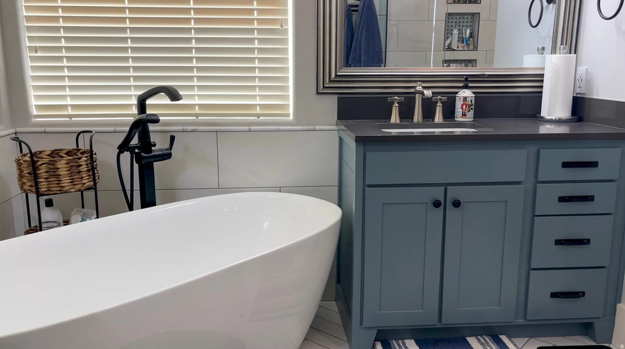 Bathroom with vanity, a soaking tub, and tile walls
