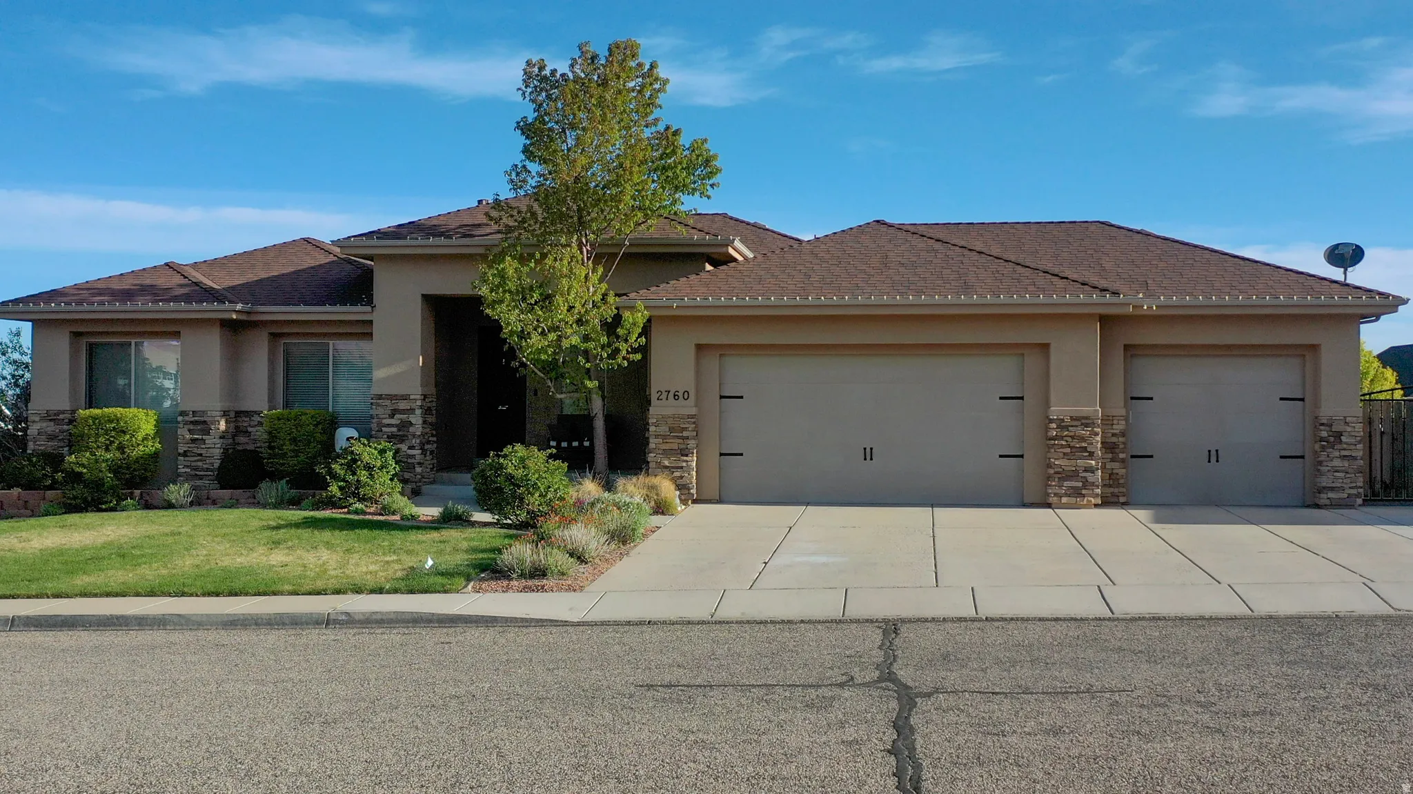 View of front of home featuring stone siding, stucco siding, an attached garage, a front lawn, and driveway