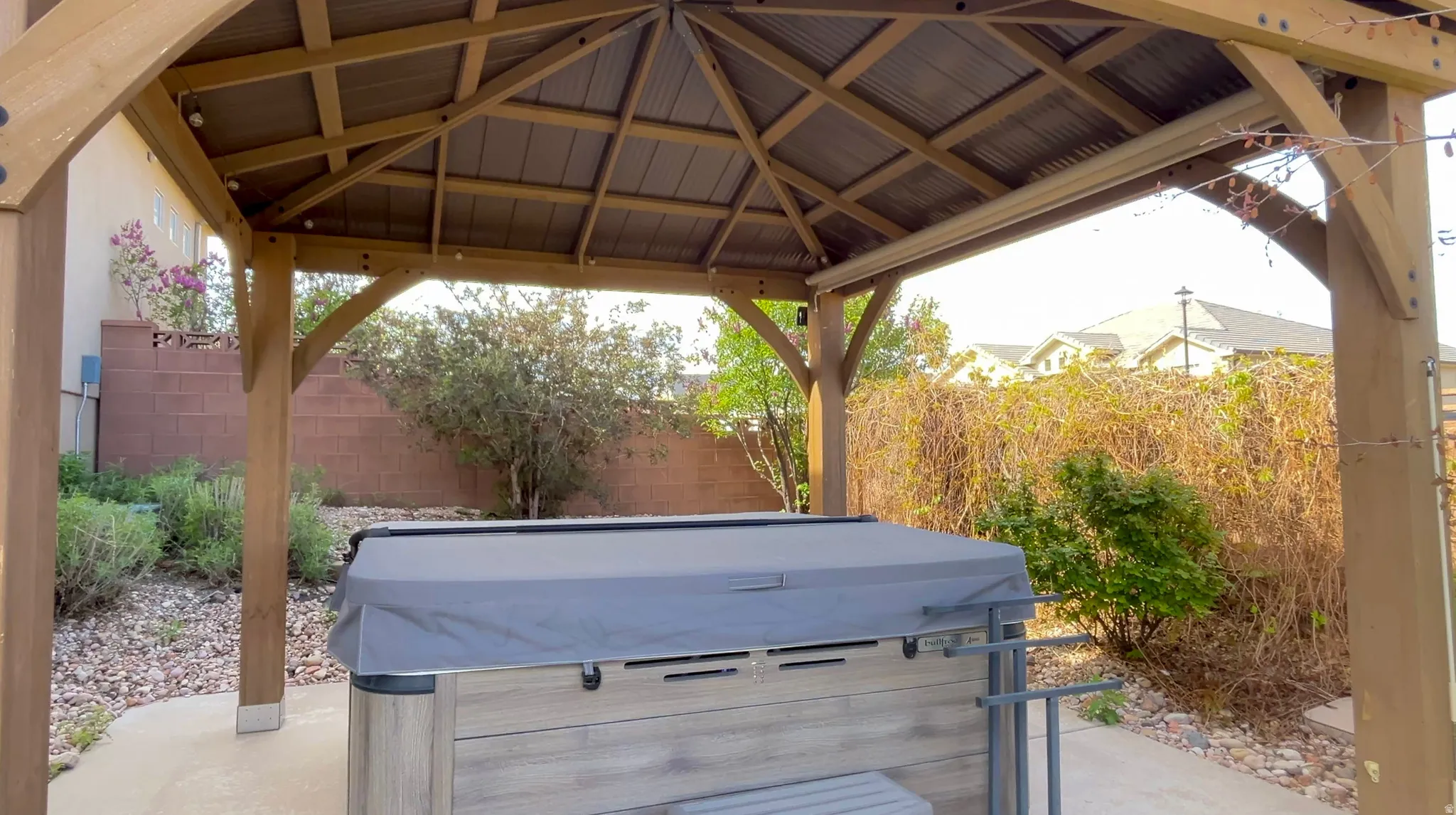 Fenced backyard featuring a patio area, a gazebo, and a hot tub