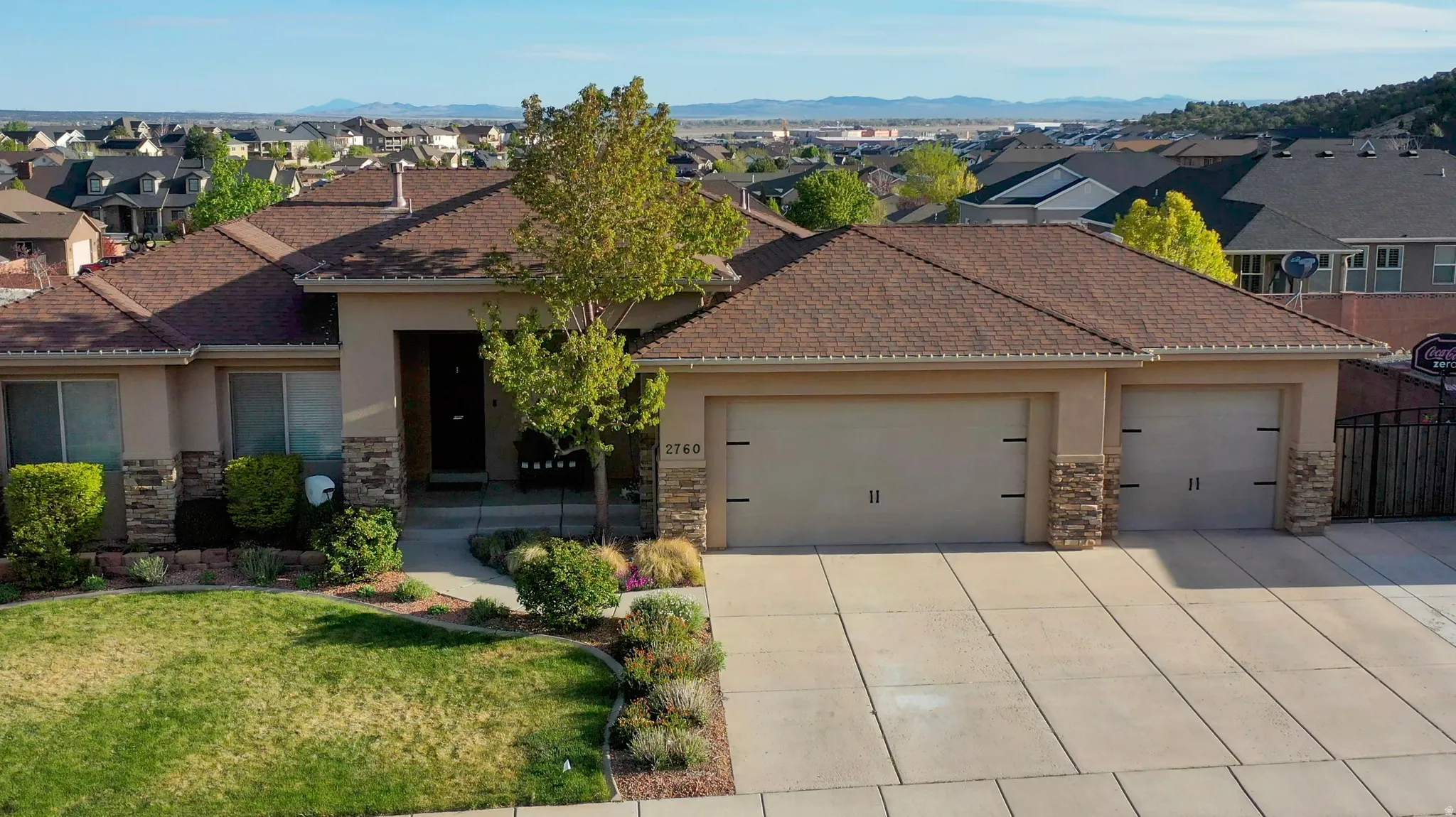 View of front facade with stone siding, stucco siding, an attached garage, driveway, and a front yard