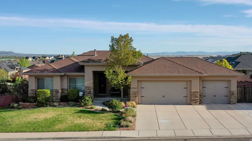 View of front of home with stone siding, stucco siding, a garage, a front lawn, and driveway