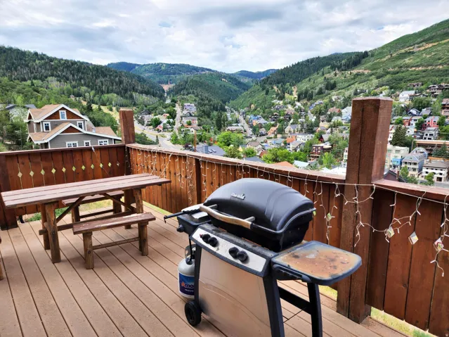 Deck with area for grilling, a mountain view, outdoor dining space, and a residential view