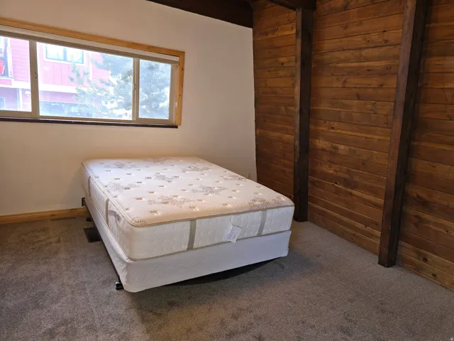 Carpeted bedroom featuring wood walls