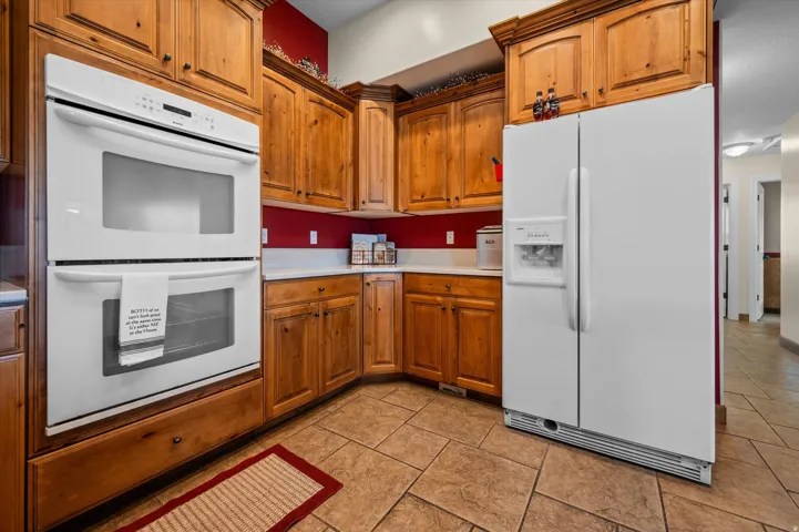 Kitchen with white appliances, light countertops, and wood finish cabinets