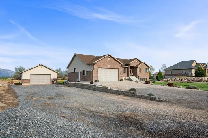 View of front of house featuring brick siding, a garage, an outbuilding, and driveway
