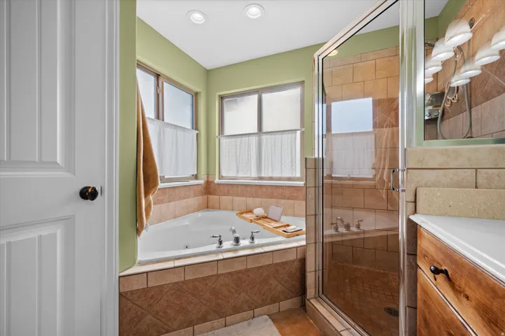 Bathroom with vanity, a tub with jets, and a shower stall