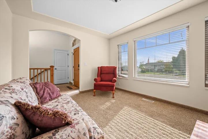 Sitting room with arched walkways, light colored carpet, and an upstairs landing