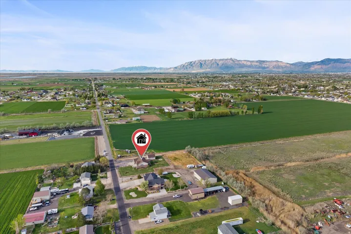 Aerial view of sparsely populated area with a mountain backdrop and rows of crops