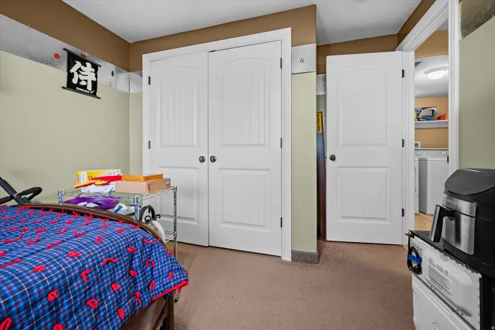 Bedroom with light colored carpet, washer / clothes dryer, and a closet