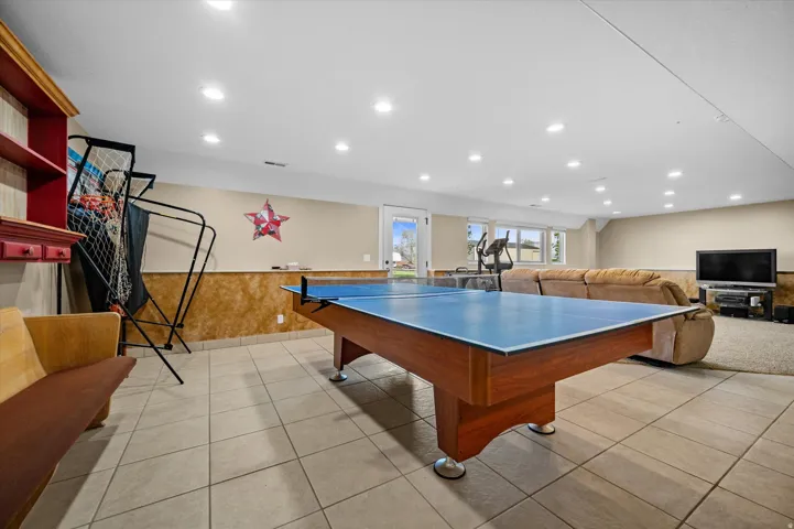 Recreation room with a wainscoted wall, recessed lighting, light tile patterned flooring, and wood walls