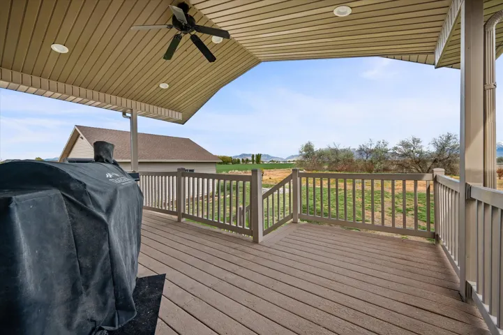 Wooden terrace featuring area for grilling and ceiling fan