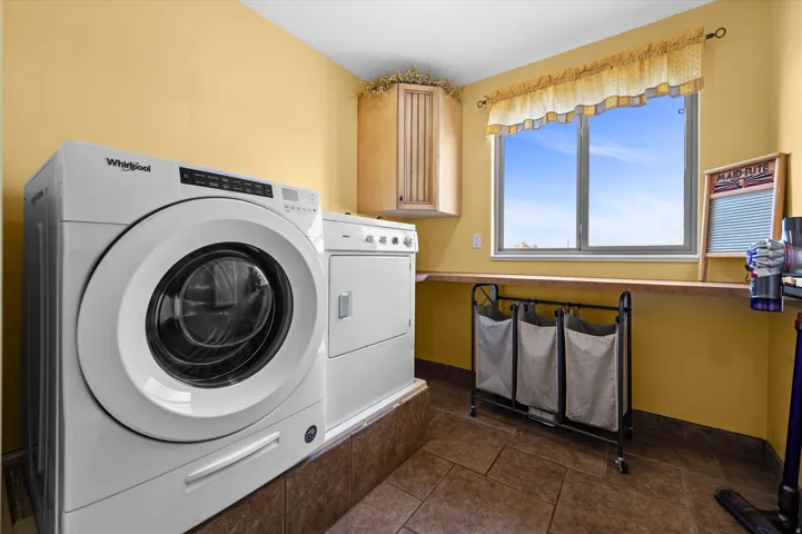 Laundry area featuring washer and dryer, cabinet space, and dark tile patterned flooring