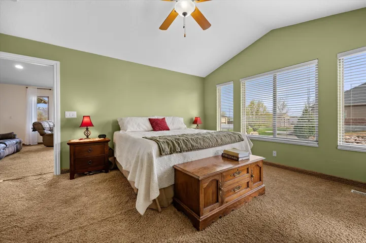 Bedroom with carpet flooring, vaulted ceiling, and ceiling fan