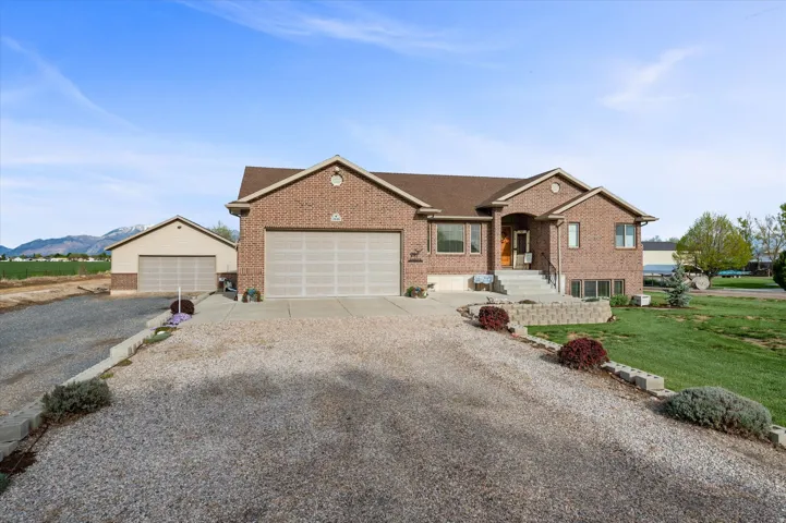 Single story home featuring brick siding, gravel driveway, and a front lawn
