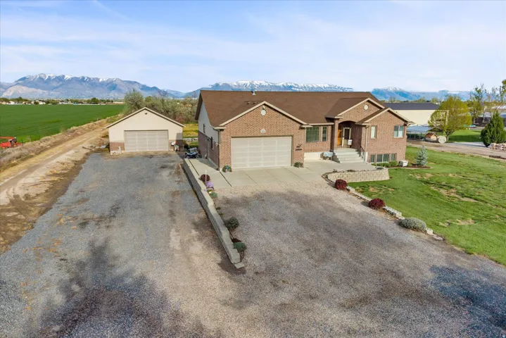 Ranch-style house with a detached garage, brick siding, a front lawn, and a mountain view