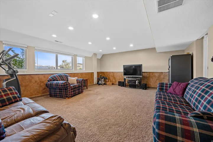 Carpeted living area featuring wainscoting, wood walls, and recessed lighting