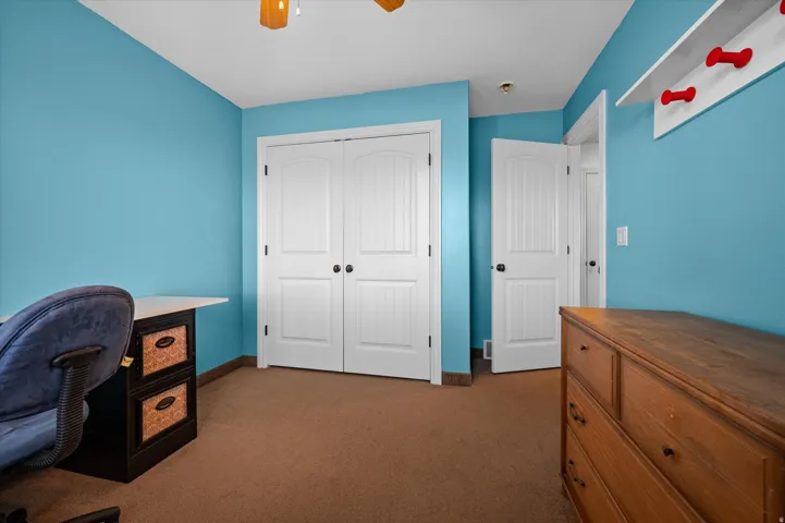 Office area with dark carpet and ceiling fan