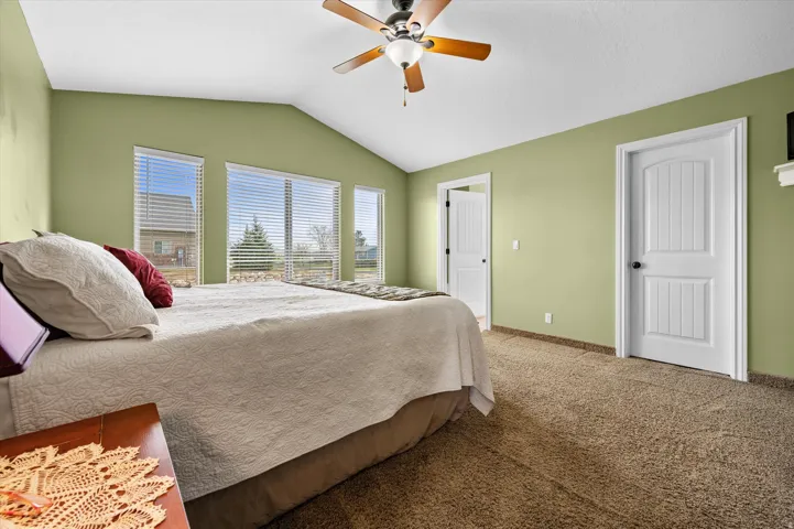Carpeted bedroom with a ceiling fan and baseboards