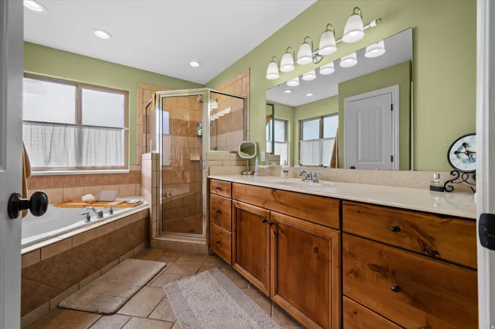 Bathroom featuring vanity, a stall shower, a bath, and recessed lighting