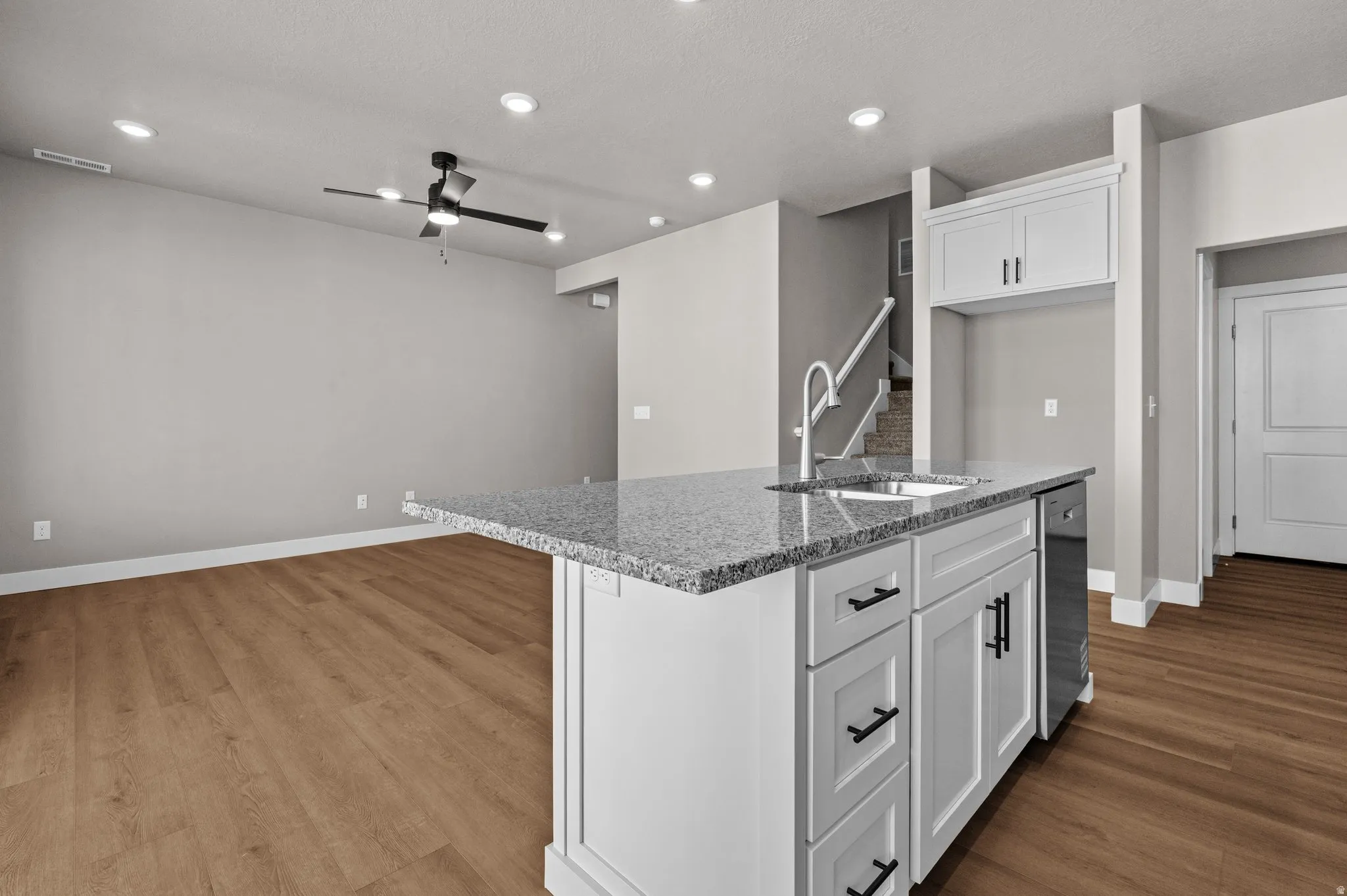 Kitchen island with a granite countertop, undermount sink, and integrated dishwasher