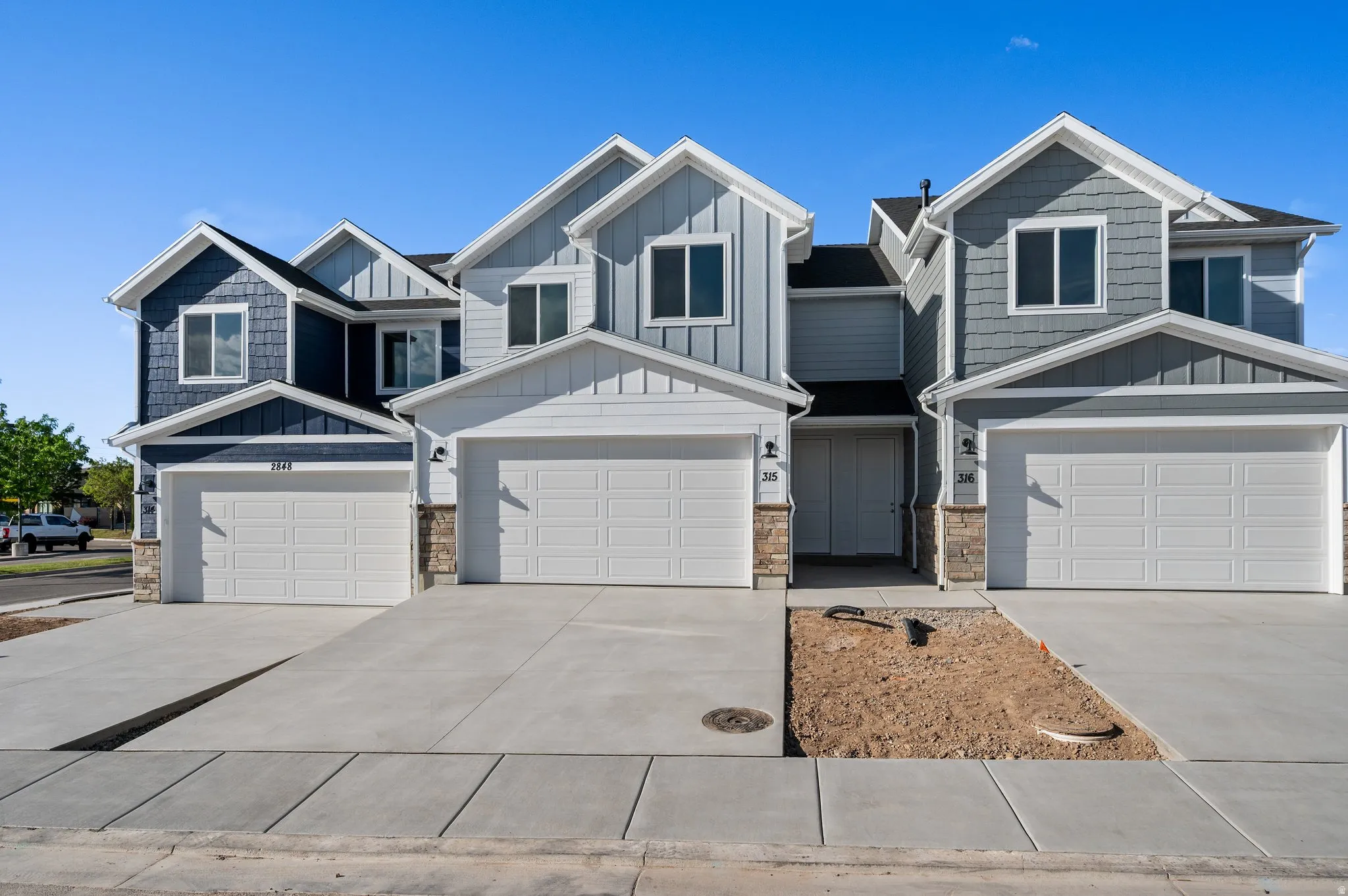Contemporary townhome exterior featuring multi-toned siding, stone accents, and gabled rooflines