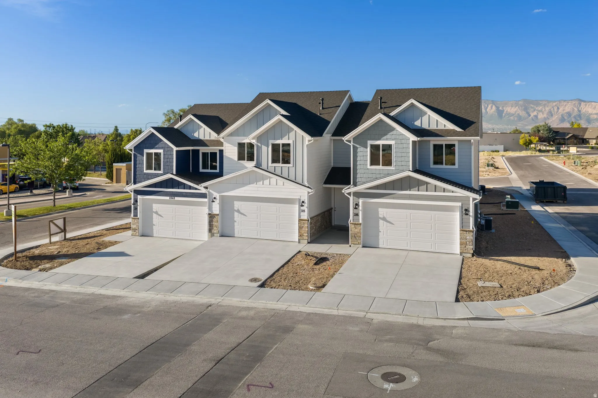 Contemporary townhomes featuring varied siding finishes, gabled roofs, and attached garages